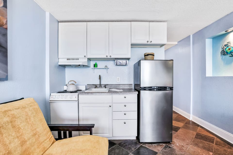 Fully equipped kitchenette with refrigerator, stove, sink, and storage—perfect for a convenient beach stay. Prepare meals with ease and enjoy coastal comfort just steps from the ocean and sandy shoreline.