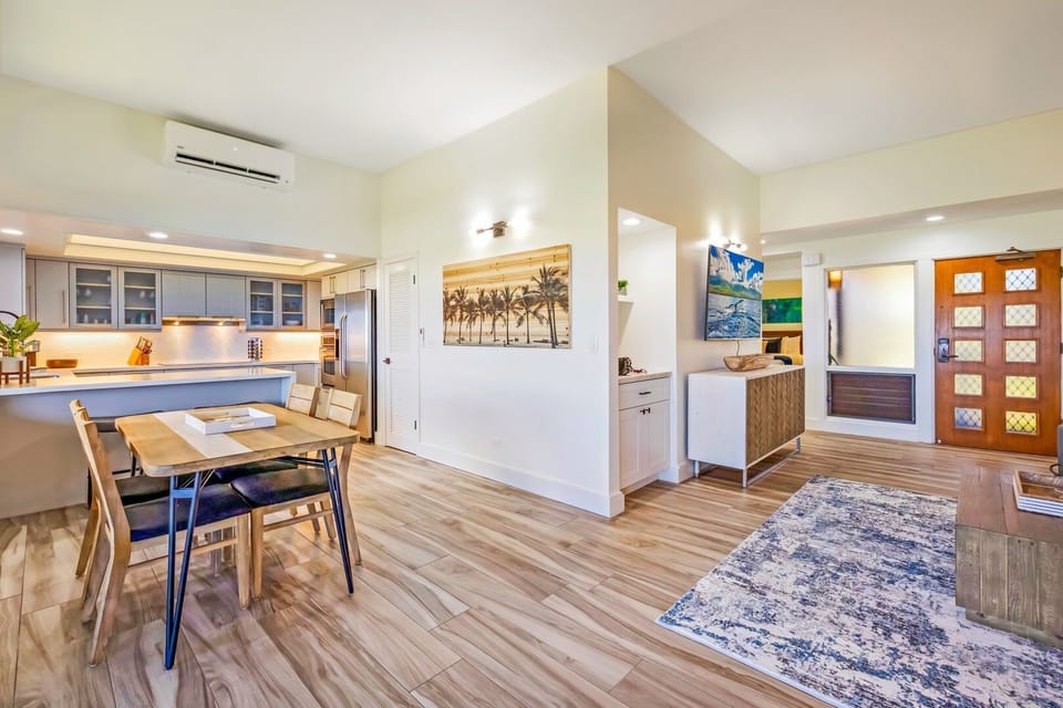 Enjoy a bright open layout where the living area flows seamlessly into the kitchen, accented by coastal artwork and warm wood tones.