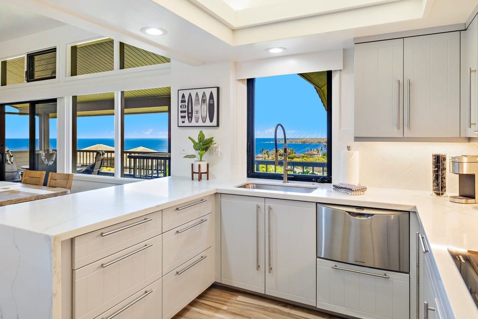 Prepare meals in a modern kitchen featuring sleek white cabinetry, stainless steel appliances, and large windows for natural light.
