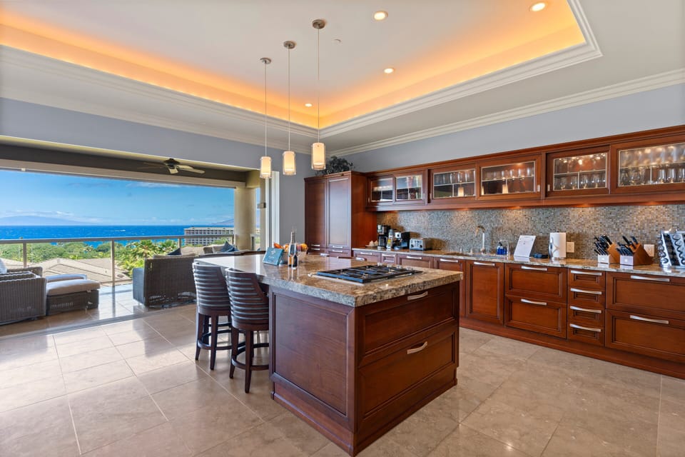 A fully equipped kitchen featuring granite countertops, rich cabinetry, and breathtaking ocean views
