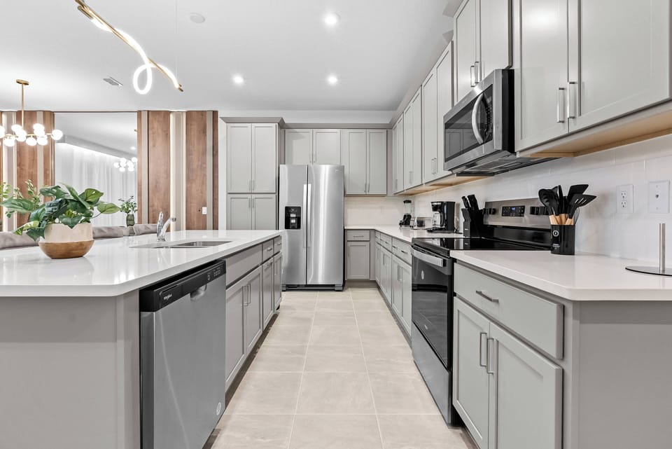 This stylish kitchen features light gray cabinetry and warm wood accents, creating a functional space. With modern stainless steel appliances and elegant pendant lighting, it's designed to inspire your culinary creativity.
