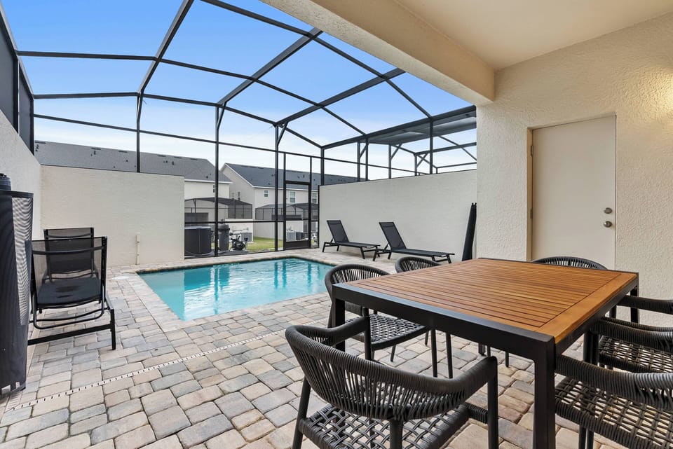 Enjoy your private outdoor oasis with a sparkling pool, elegant pavers, and stylish black wicker furniture. It's the perfect space for sunny afternoons or evening gatherings under the stars.