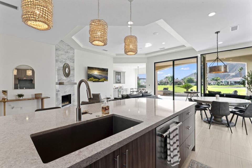 Open gourmet kitchen w/ large island & panoramic windows framing scenic views