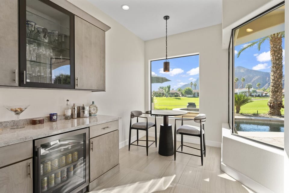 Stylish wet bar area w/ sink, cabinetry & bright window views for casual drinks