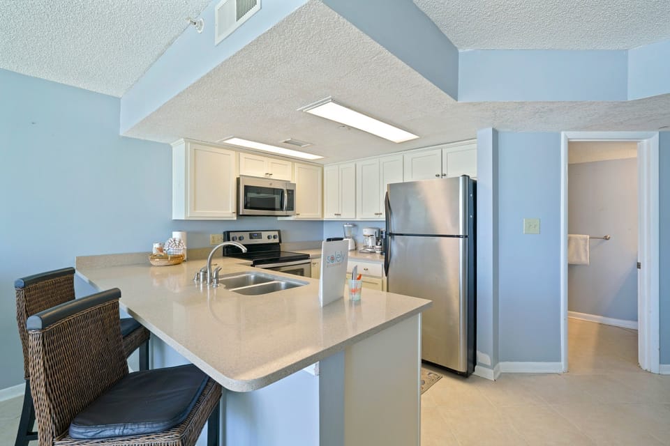 The open-concept kitchen and living area at Cabana Club 304 features quartz countertops, full appliances, and stunning Gulf views from the balcony.