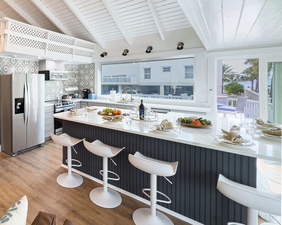“A bright, open kitchen with a six-seat island and a picture window framing uninterrupted views of the coastline.”