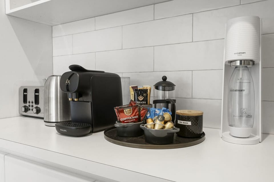 A well-stocked coffee and tea station with a capsule machine, French press, kettle, toaster, and SodaStream. Everything you need to start the morning is set out and ready on the kitchen benchtop.