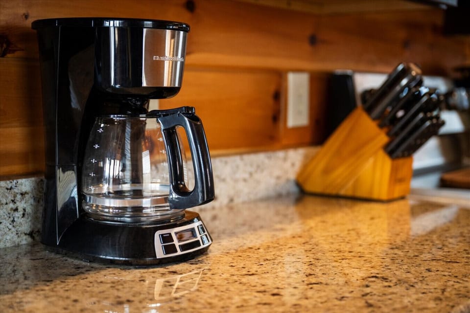 Start your morning slow with fresh coffee brewing in a warm, cabin-style kitchen. Granite counters, natural wood, and everything you need to ease into the day.