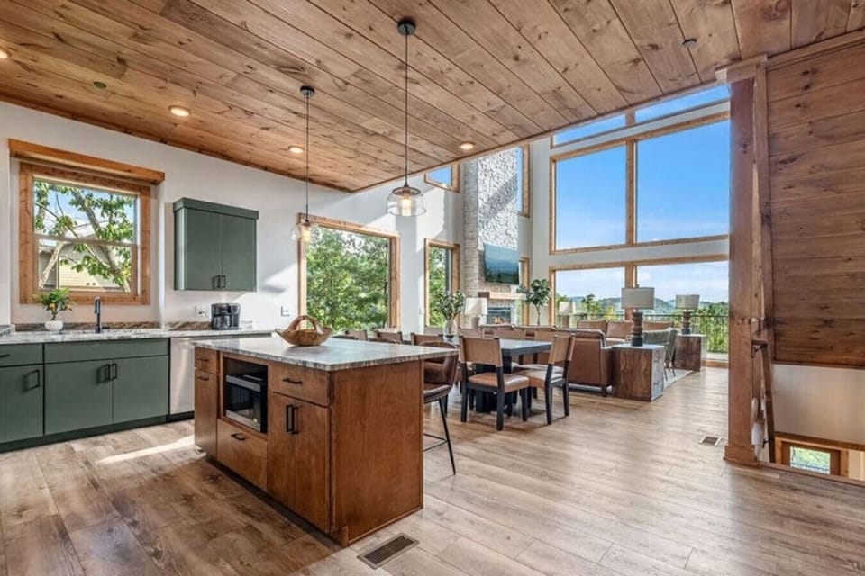 Vaulted ceilings and a wall of windows flood the main level with natural light. The kitchen, dining, and living spaces flow together beautifully, making it easy to gather while still enjoying the views.