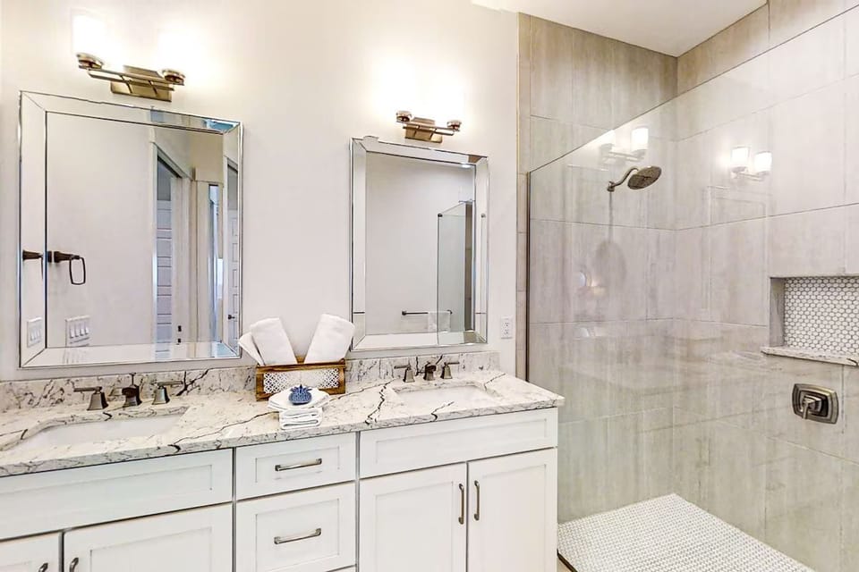 Bathroom featuring a double vanity and a glass-enclosed walk-in tile shower.