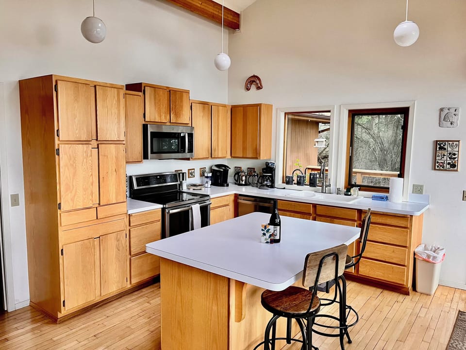 Open kitchen with island seating, forest and panoramic water views.
