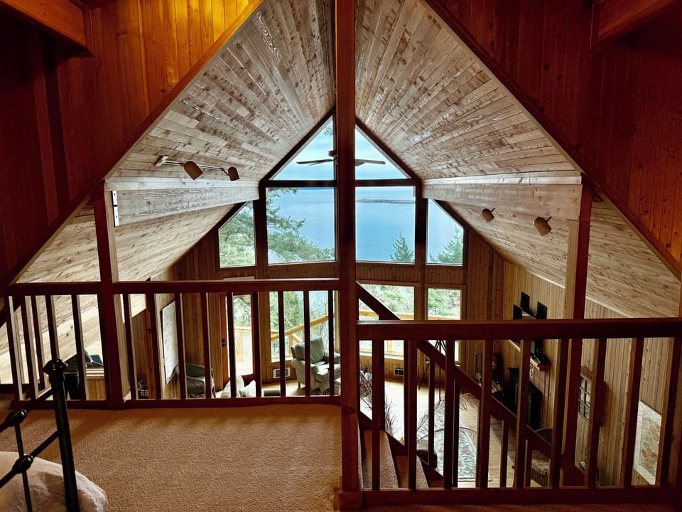Upstairs loft bedroom with queen bed and panoramic water views, half bath. 
