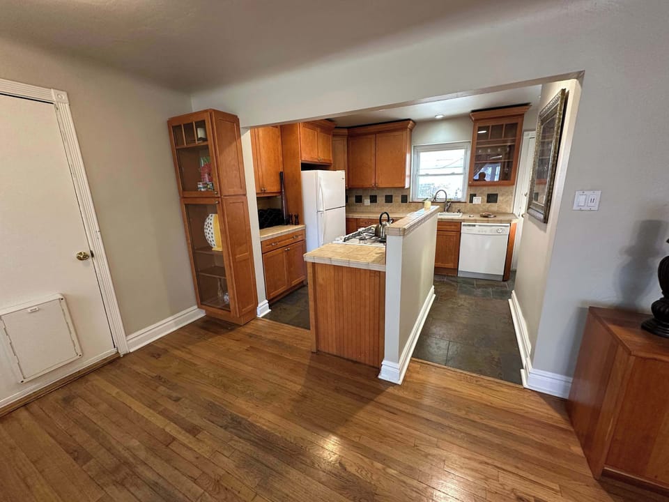 Wide view showing the seamless transition from the hardwood-floored living area into the tiled kitchen. This open-concept design maximizes the sense of space and light throughout the main floor.
