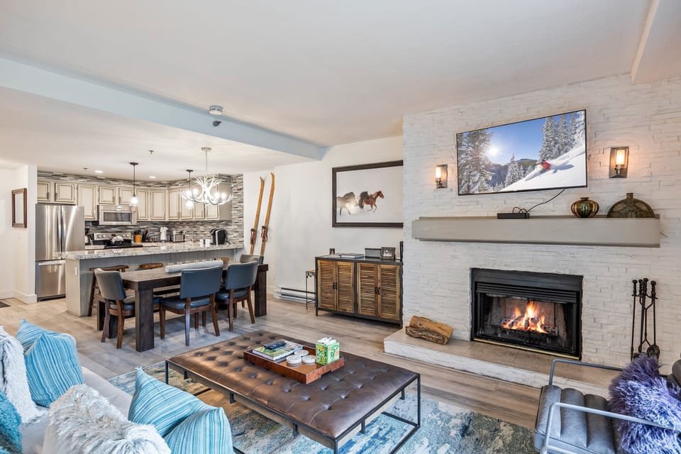 Bright and inviting living area featuring a wood fireplace, comfortable seating, and seamless flow into the kitchen and dining space—