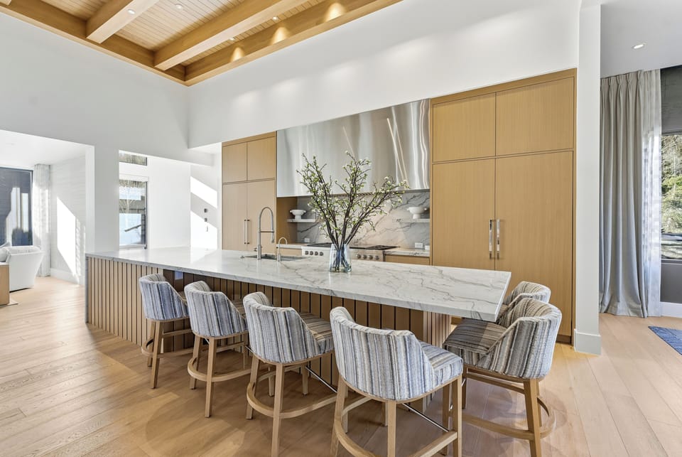 Elegant dining room with light wood flooring, modern chandelier, and oversized windows bringing in natural light.