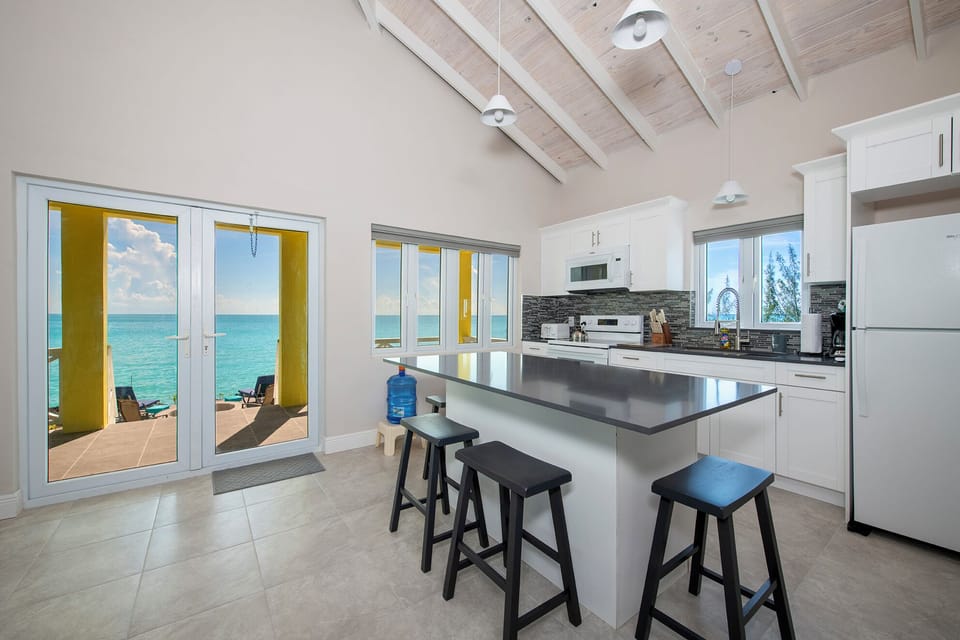 Guest Cottage living area opens through French doors onto a large sea-front porch furnished with Adirondack chairs.