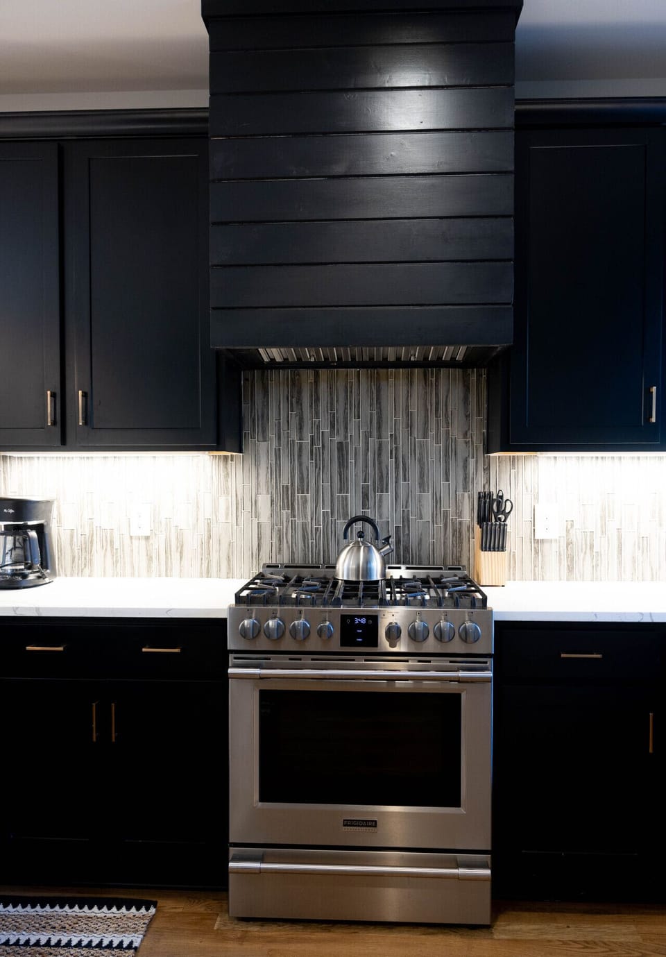 Sleek kitchen backsplash with under-cabinet lighting over the stovetop area.