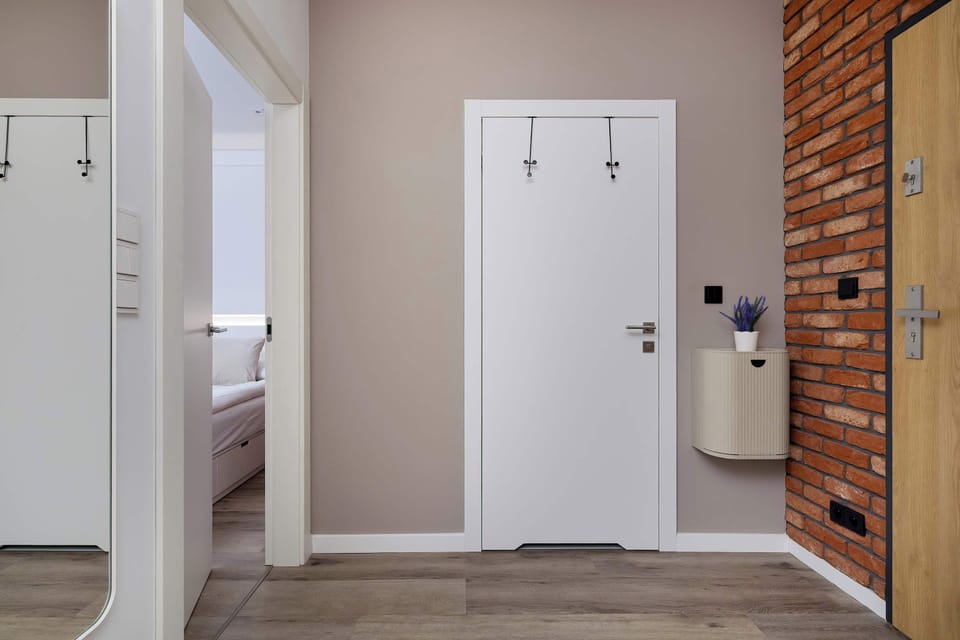 The spacious hallway with a brick wall and coat hooks provides a convenient spot to leave your outerwear right after entering.