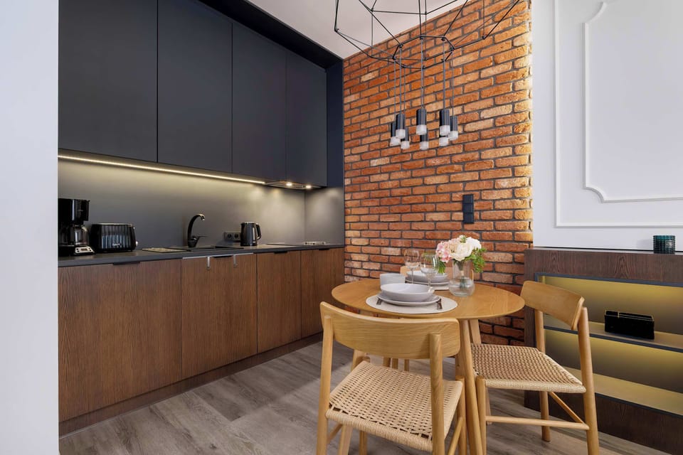 The dark kitchen cabinetry contrasts beautifully with the brick wall, creating a modern yet warm space for cooking together.