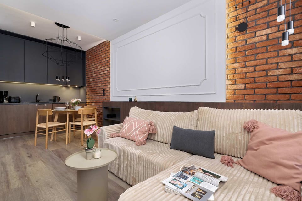 A comfortable sofa with pastel cushions invites relaxation after a busy day, while the brick wall adds character to the room.