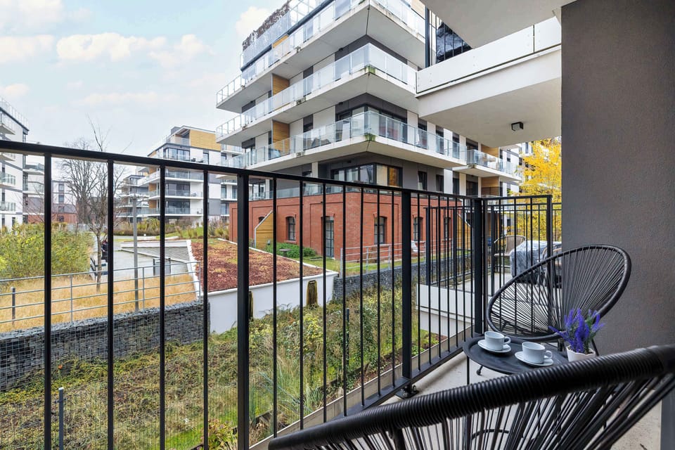 The furnished balcony overlooking greenery invites you to enjoy your morning coffee and a moment of relaxation outdoors.