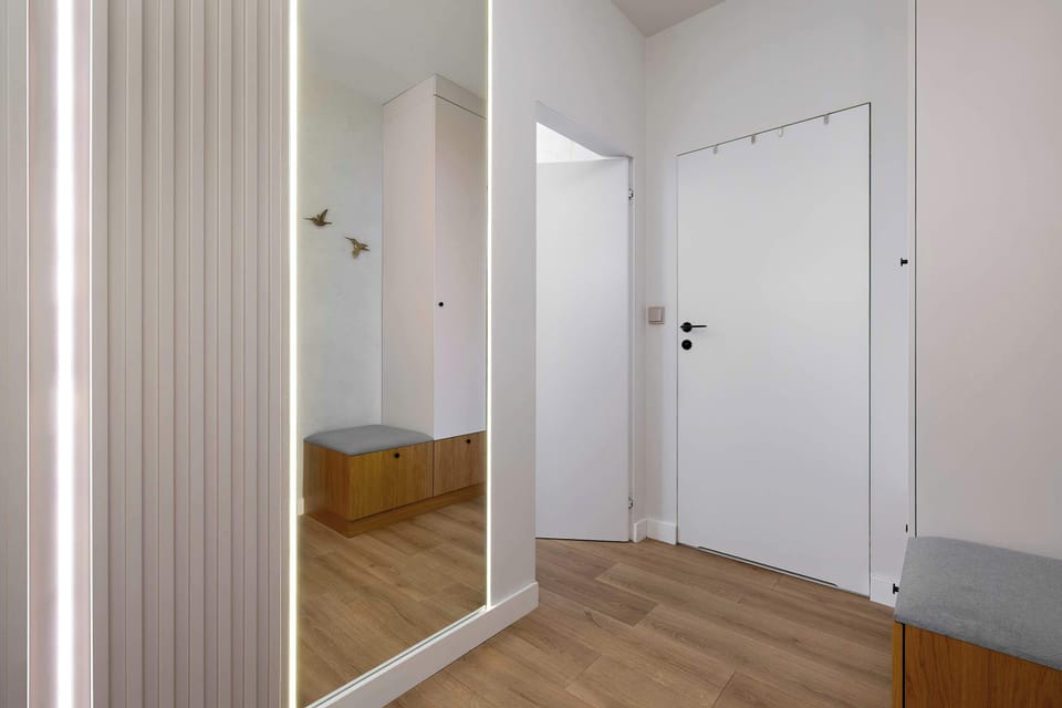 The spacious hallway with a large mirror and bright lighting welcomes guests with elegance and a sense of order.