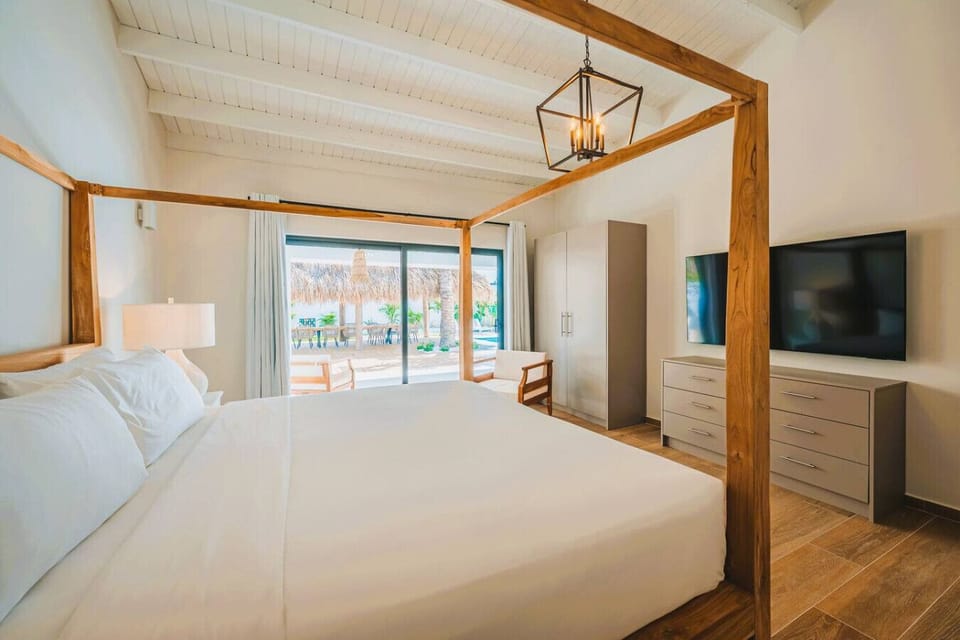 Master bedroom 1 overlooking the pool with ensuite, canopy bed, large closet, dresser and 65` TV
