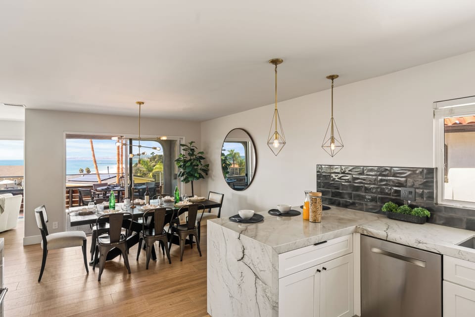 Stylish open-concept kitchen and dining area with marble island, modern lighting, and ocean views. (Unit 1)