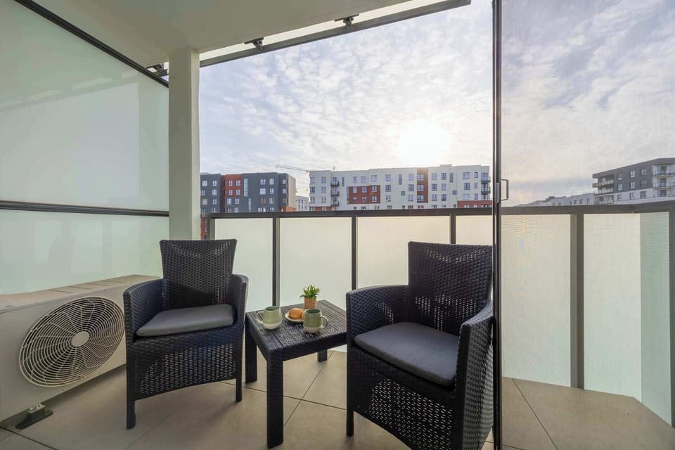 Enclosed balcony furnished with armchairs and city views.