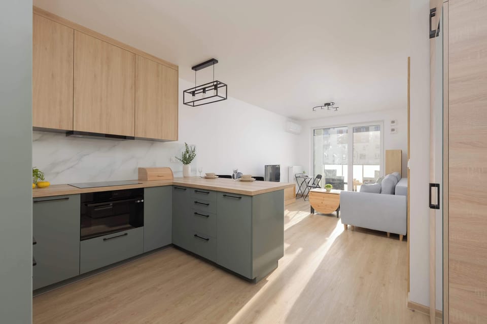 View of the kiKitchen corner with built-in oven, induction hob, and dining space.tchen with gray cabinets, wooden elements and a functional layout.