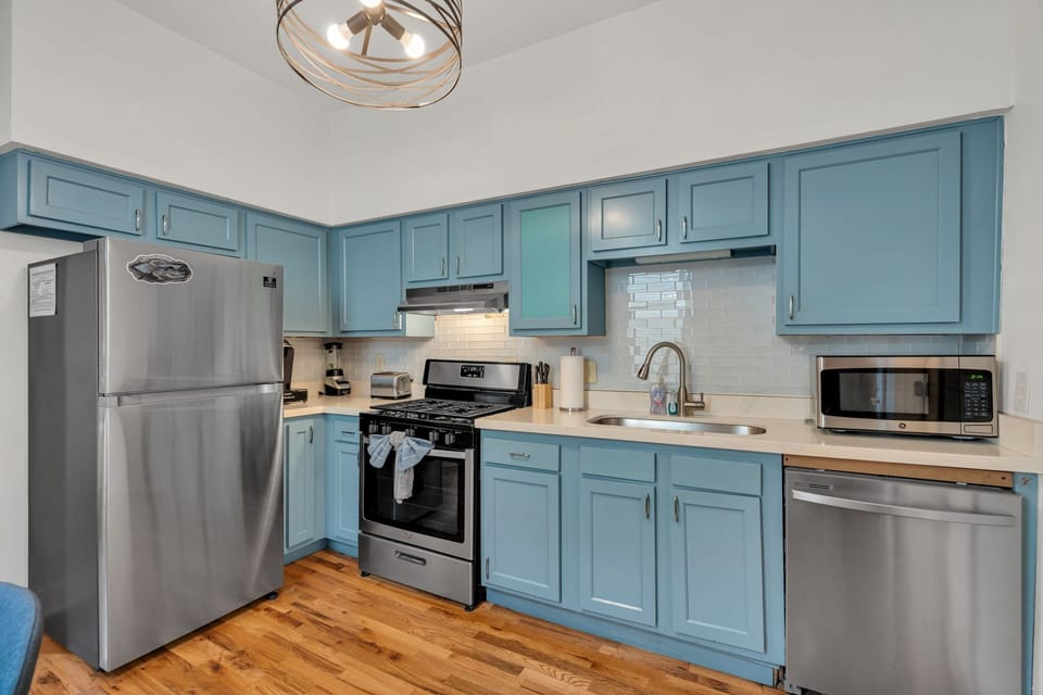 Fully equipped kitchen w/ stainless steel appliances & blue cabinetry.
