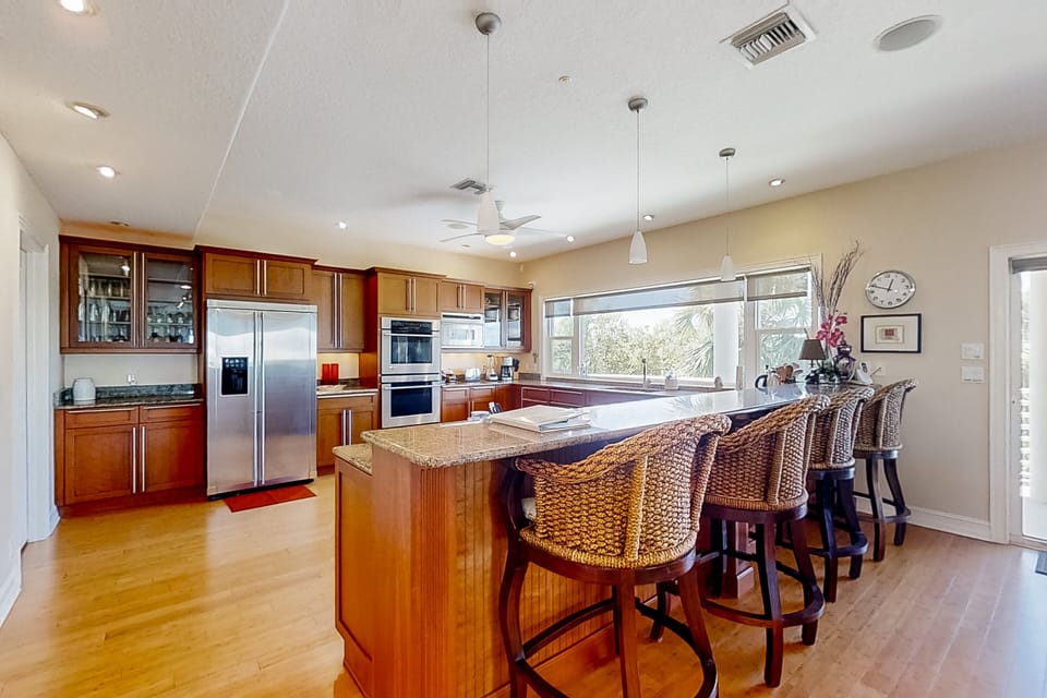 Enjoy your beach stay with this spacious, fully equipped coastal kitchen featuring modern appliances, ample seating, and an open layout—ideal for preparing meals and gathering after a day of sun and sand.