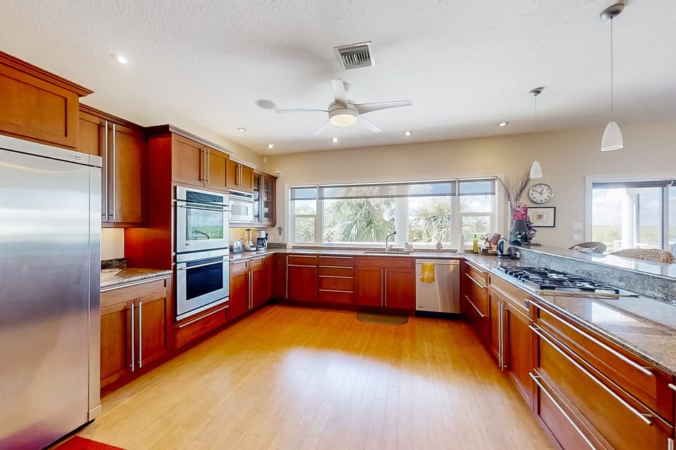 Enhance your beach stay in this sunlit coastal kitchen, featuring modern appliances, generous counter space, and palm-lined views—perfect for cooking, entertaining, and relaxing after a day at the beach.