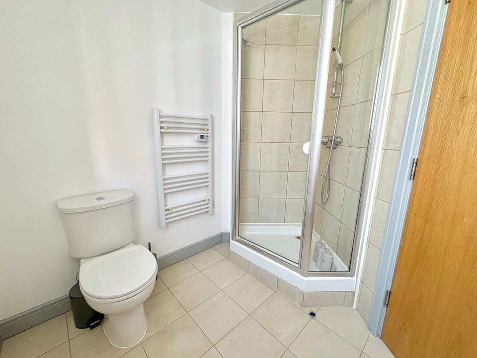 Ensuite bathroom with glass shower enclosure, toilet, and sink, offering a fresh and convenient space for our guests.