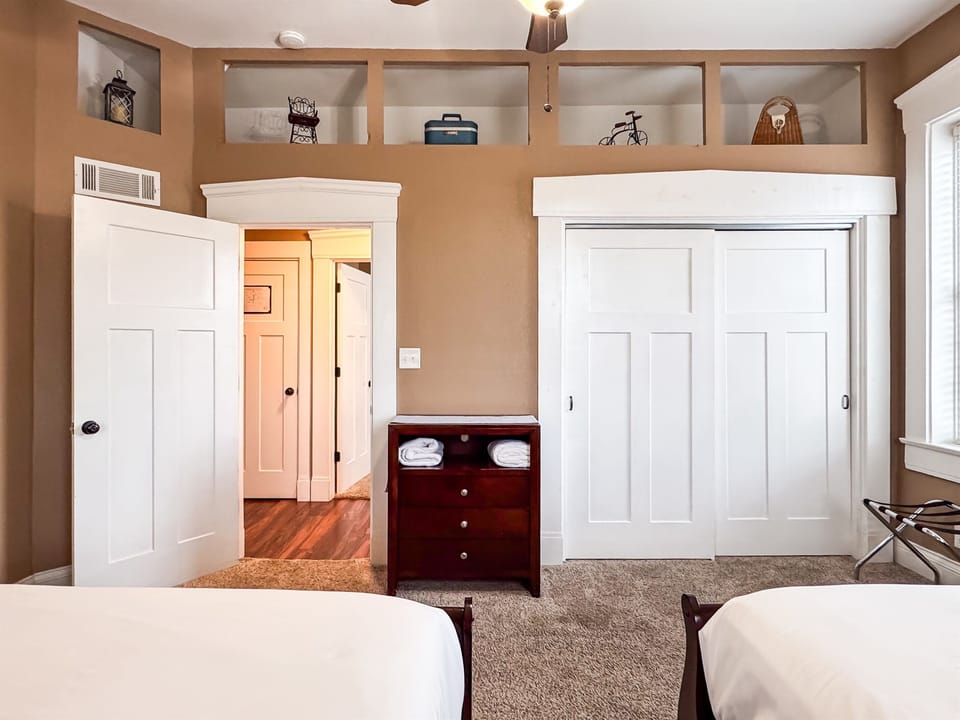 Spacious main level bedroom includes two plush queen size beds with crisp white linens and a full bathroom with combo tub and shower off the hallway at Aussie Cottage.
