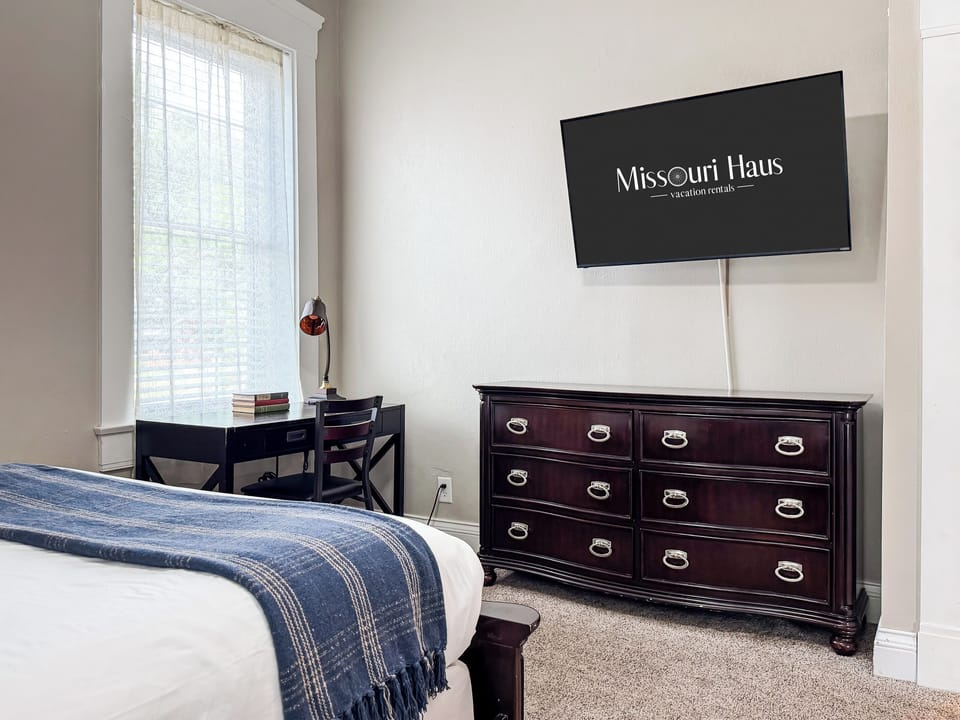 Spacious main level plush queen size bedroom with crisp white linens and full bathroom with combo tub and shower off the hallway at Mini Aussie Cottage.