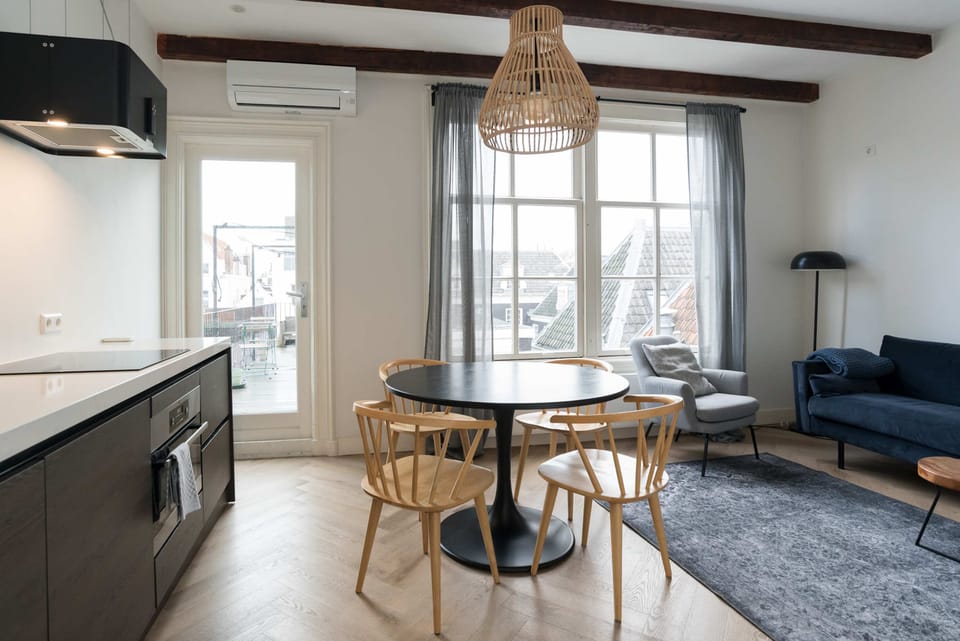 Open-plan layout with a dining table, large windows, and fully equipped kitchen.