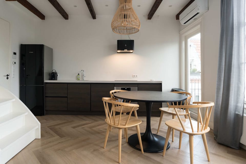 Bright dining area with natural light, Scandinavian-style furniture, and a sleek modern kitchen — ideal for relaxed mornings or cozy dinners.