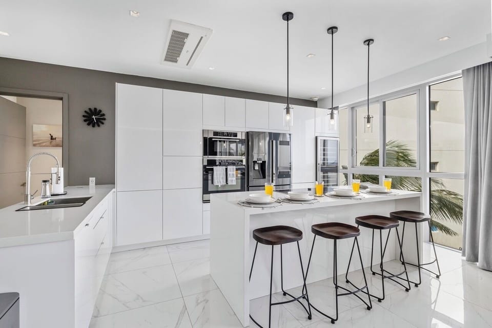 Step into your bright, modern kitchen where sleek white cabinets meet state-of-the-art appliances. Pull up a stool at the island and savor your morning coffee as tropical breezes drift in from your private balcony.