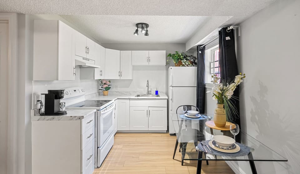 “White, full kitchen with stove, microwave, and plenty of prep space stocked with cookware, Keurig + drip coffee for easy meals.”