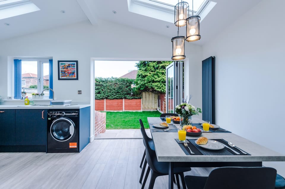 Spacious open-plan kitchen and dining area bathed in natural light from the skylights above