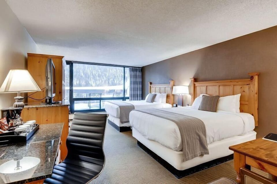 Experience the cozy charm of mountain living in this pet-friendly hotel room, featuring two queen beds and a spacious patio perfect for family relaxation.