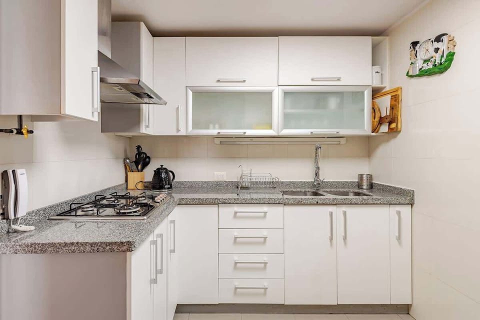 Modern kitchen with sleek white cabinets and granite countertops, perfect for culinary enthusiasts.