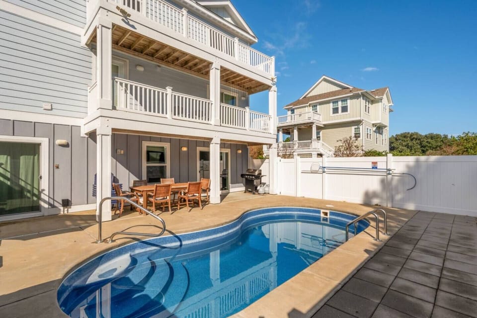 Sunlit pool deck w/ loungers & grill, ideal for easy afternoons after the beach