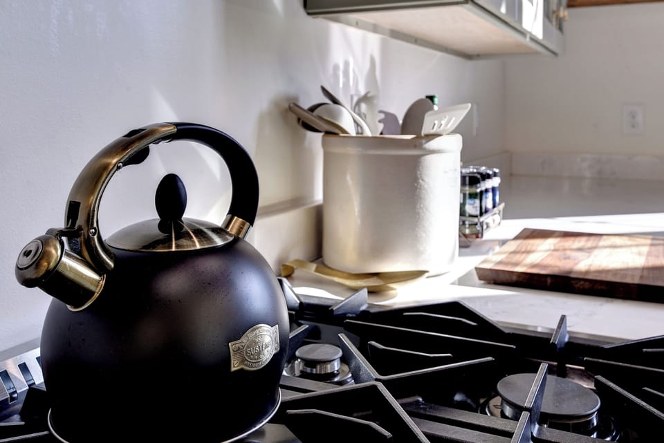 Chef-ready kitchen with gas range, kettle, spices, and sunlight.
