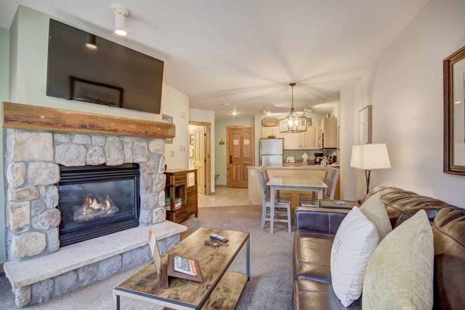 Rustic stone fireplace and leather furnishings create a cozy living space with warm lighting perfect for unwinding in any season.