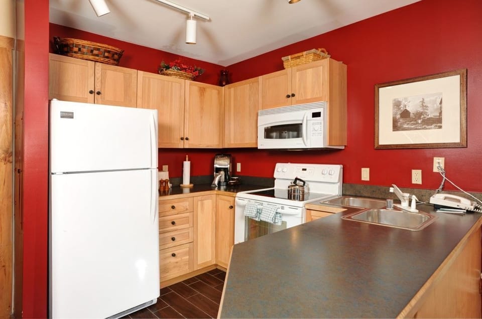 Well-equipped kitchen with rich red accents and modern appliances, perfect for preparing family meals in comfort.