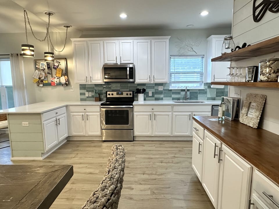 White cabinets, ocean tiles, wood accents, and beachy decor create a fresh vibe.