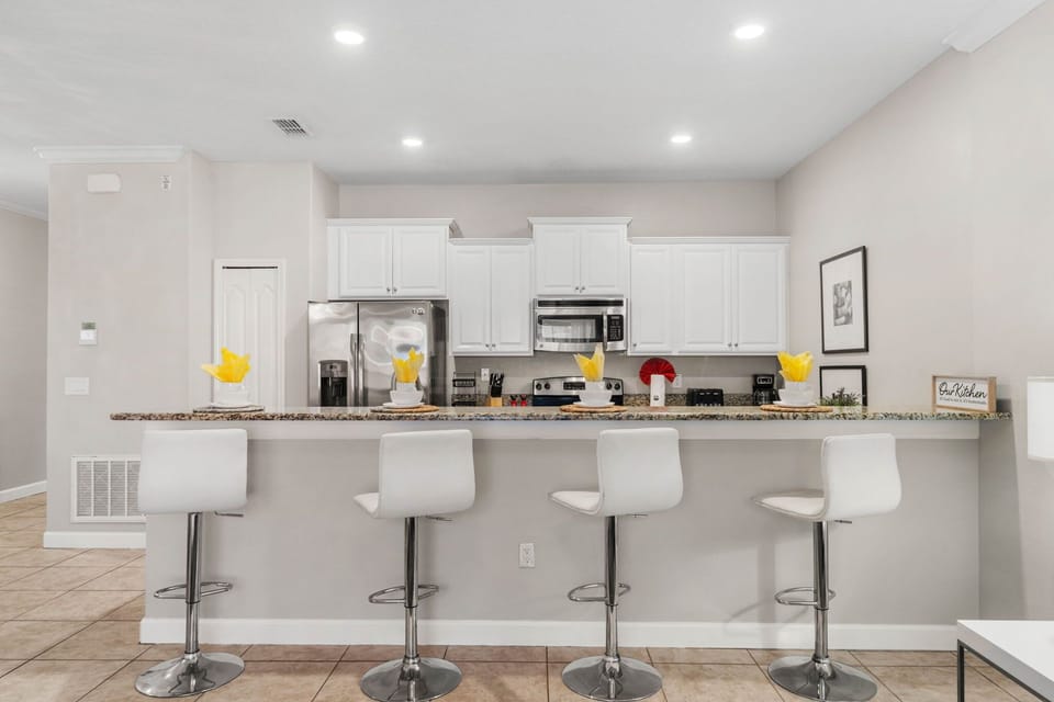 Sleek, modern kitchen with stainless appliances, white cabinetry, and a granite bar for four-perfect for morning coffee or happy-hour snacks.
