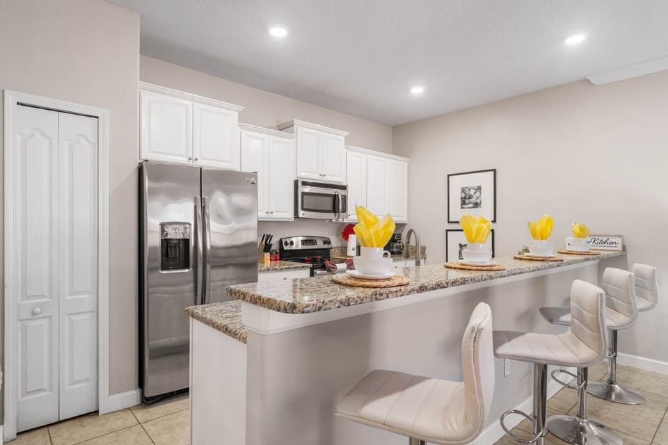 Fully equipped kitchen with granite counters, pantry, and comfy stools-light, contemporary style ready for your family feasts.
